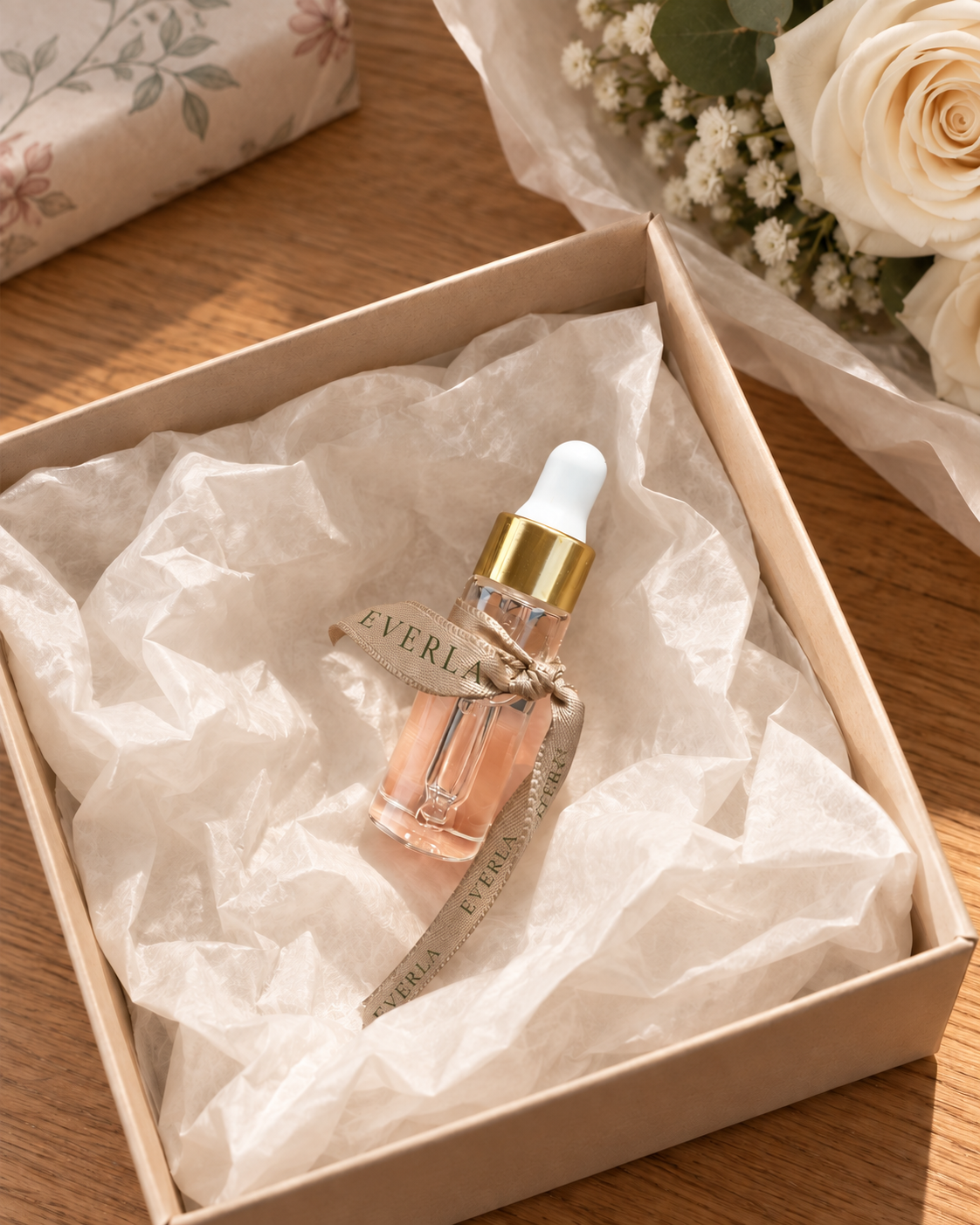 EVERLA Petit Souvenir floral perfume — decorative scene with the mini bottle in a tissue-lined gift box beside flowers; styling accessories not included.