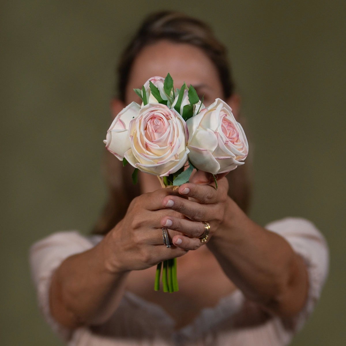 pink white premium floral bouquet luxury pre arranged artificial centerpiece lifestyle scene: person carrying or gifting bouquet