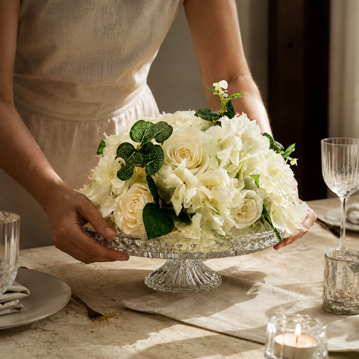 white hydrangea rose artificial arrangement premium crystal bowl centerpiece lifestyle scene: host or florist placing arrangement