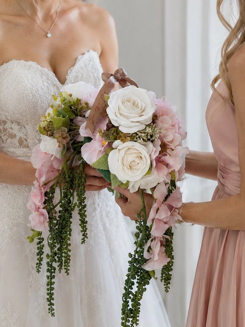 A bride holding a cascading ivory and blush floral bouquet
