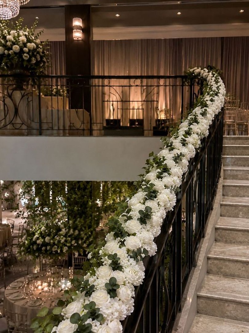 White floral garlands along a staircase at an evening venue